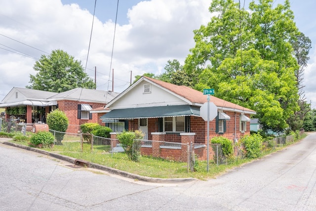 bungalow with a fenced front yard, a porch, and brick siding