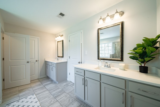 bathroom featuring a sink, two vanities, an enclosed shower, and visible vents