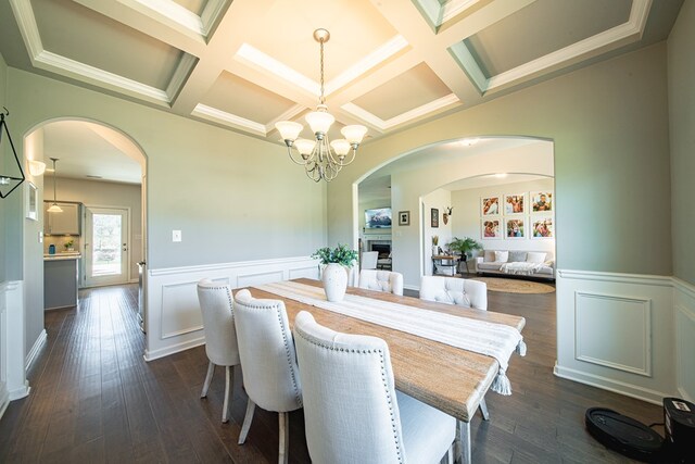 dining space with arched walkways, a notable chandelier, and dark wood finished floors