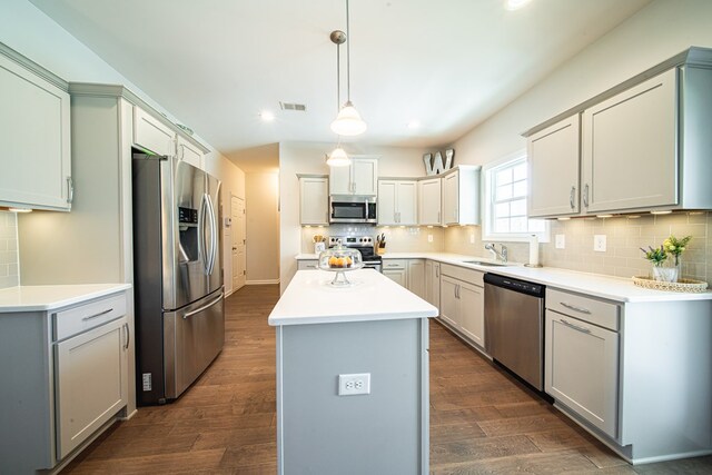 kitchen featuring visible vents, stainless steel appliances, tasteful backsplash, dark wood finished floors, and a center island