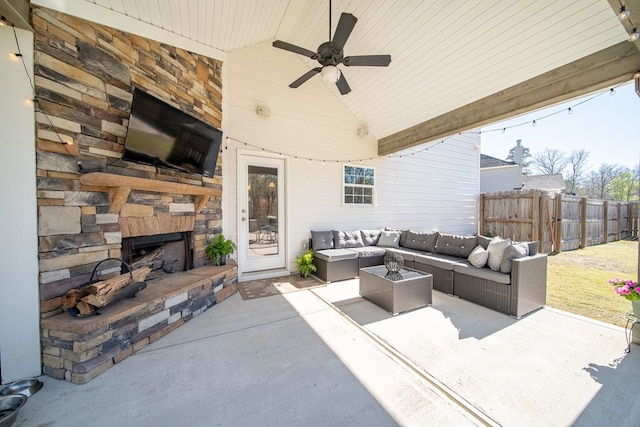 view of patio with fence, an outdoor living space with a fireplace, and a ceiling fan