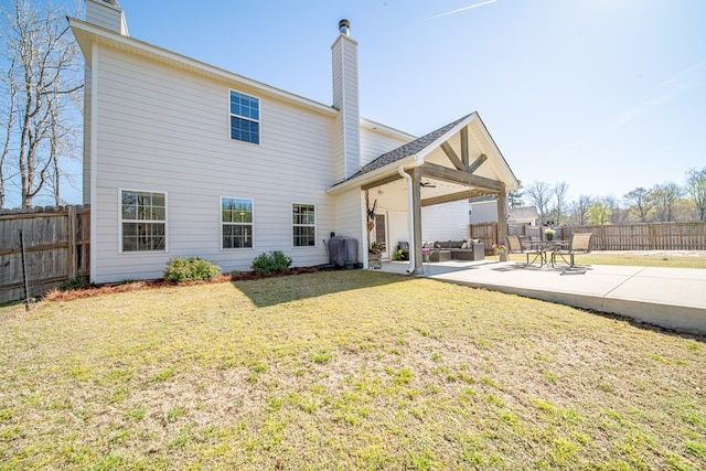 rear view of property featuring a chimney, fence, ceiling fan, a yard, and a patio area