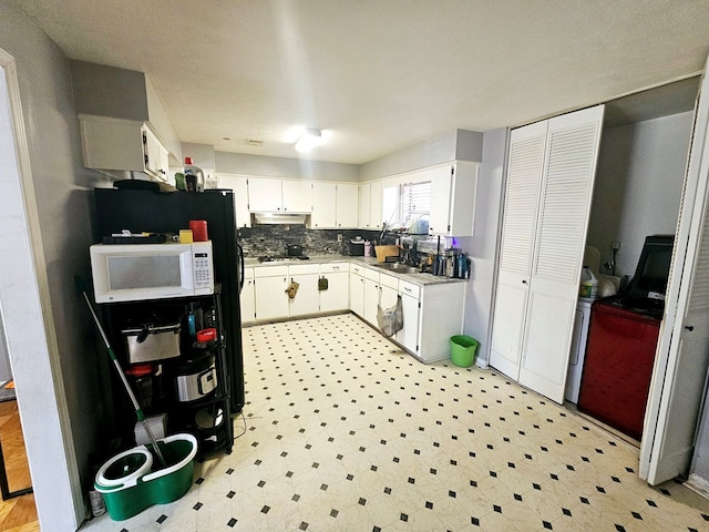 kitchen with white microwave, light floors, under cabinet range hood, white cabinetry, and a sink