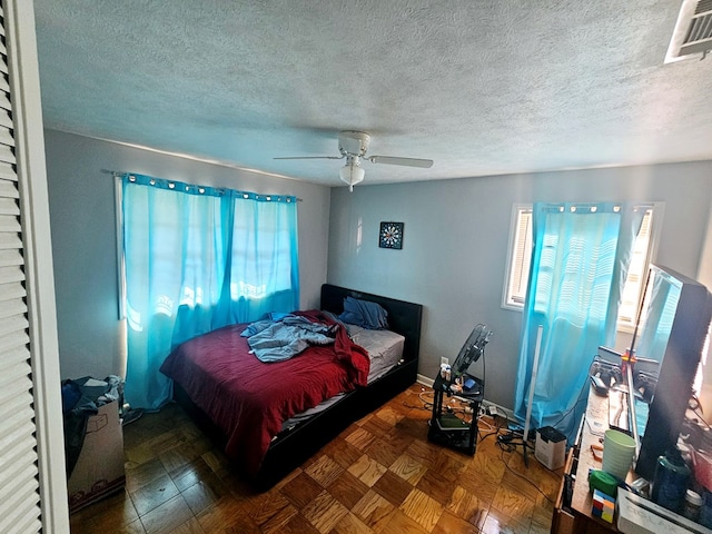 bedroom featuring a ceiling fan, visible vents, a textured ceiling, and baseboards