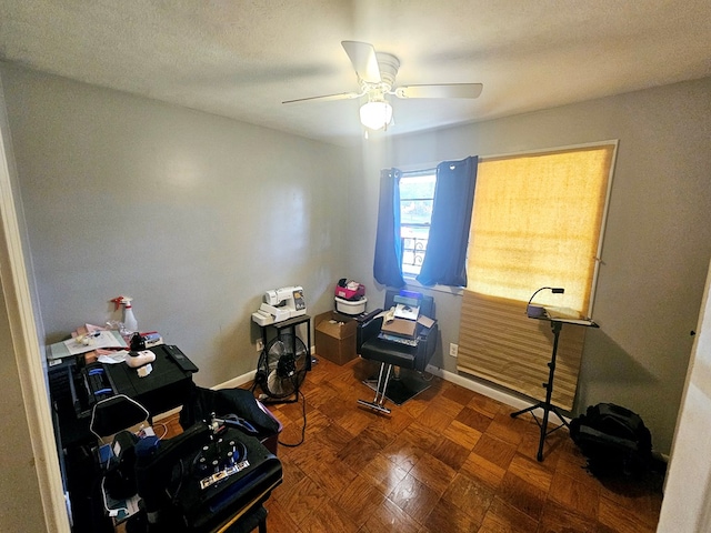 office area featuring a textured ceiling, a ceiling fan, and baseboards