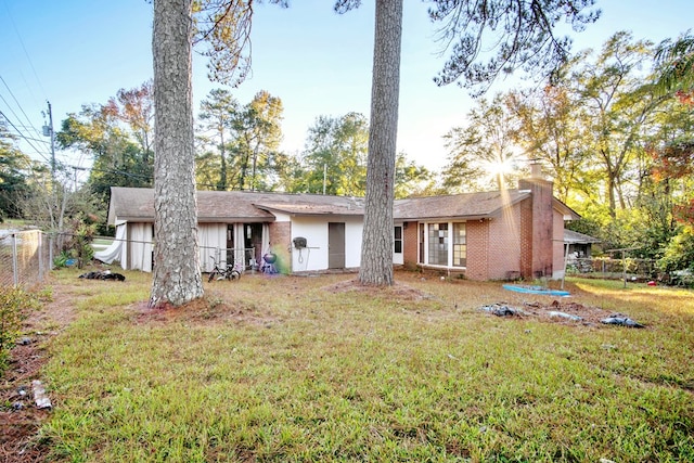 back of property featuring a yard, brick siding, a chimney, and fence