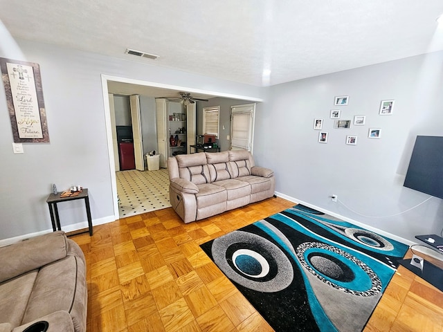 living area with a ceiling fan, visible vents, and baseboards