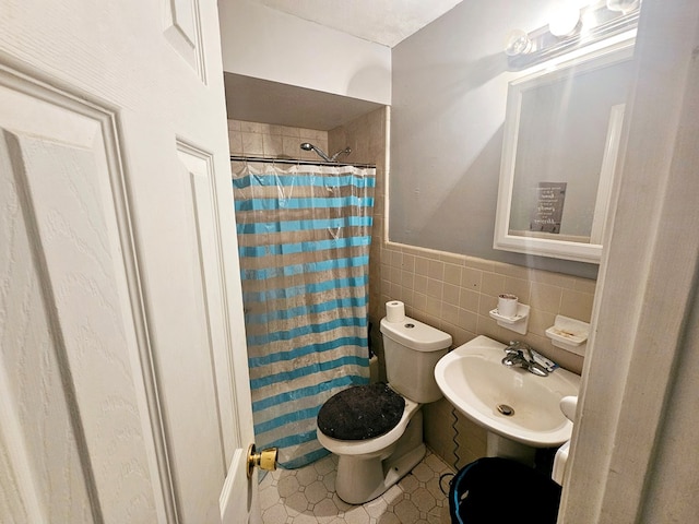 full bathroom featuring a wainscoted wall, tile walls, curtained shower, toilet, and a sink