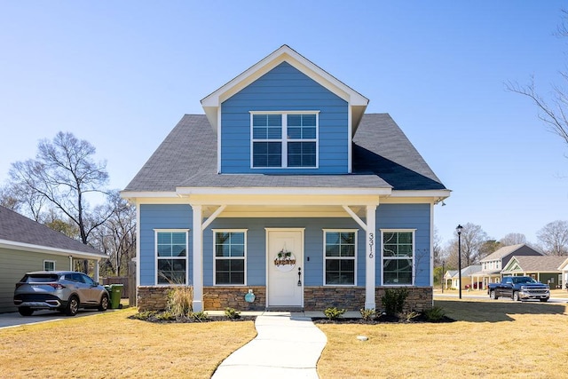 view of front of property featuring stone siding, covered porch, and a front yard