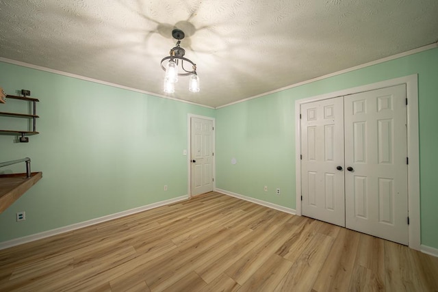 unfurnished bedroom featuring a closet, light hardwood / wood-style flooring, crown molding, and a textured ceiling