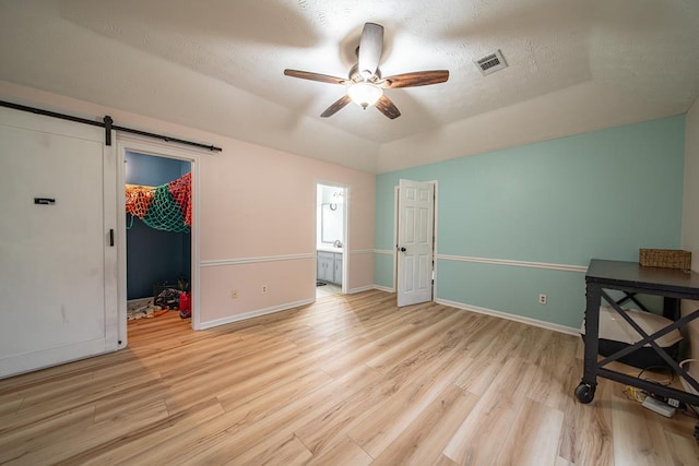 bedroom with light wood-type flooring, ensuite bath, ceiling fan, a spacious closet, and a closet