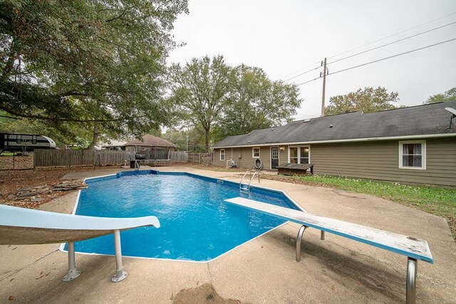 view of swimming pool with a diving board and a patio