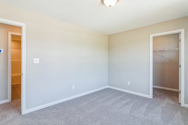 unfurnished bedroom featuring a closet, a walk in closet, and carpet floors