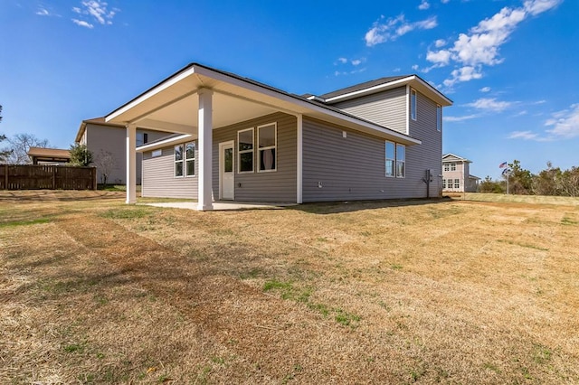 back of house with a patio and a lawn