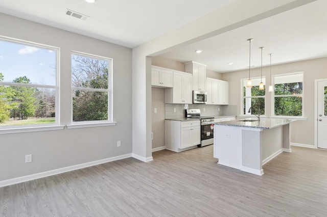 kitchen with stainless steel appliances, light stone countertops, white cabinets, pendant lighting, and a kitchen island with sink