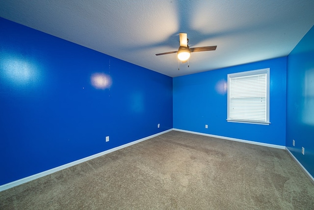 empty room with a ceiling fan, carpet floors, a textured ceiling, and baseboards