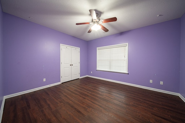 unfurnished bedroom with a textured ceiling, dark wood-type flooring, a ceiling fan, and baseboards