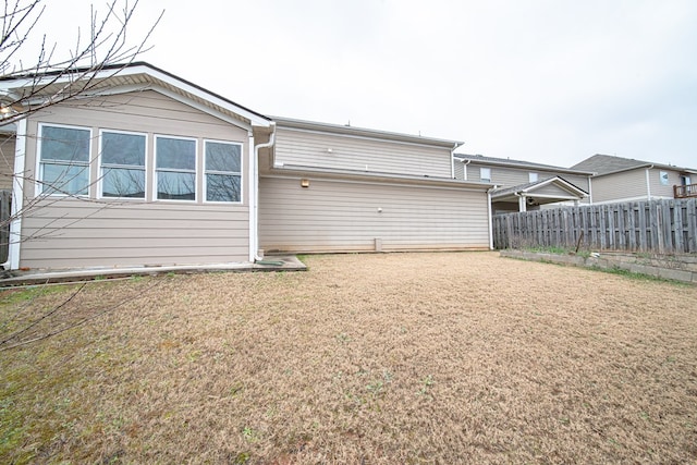 rear view of house with a yard and fence