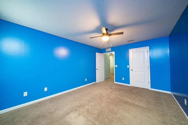 unfurnished bedroom with a textured ceiling, carpet flooring, a ceiling fan, visible vents, and baseboards