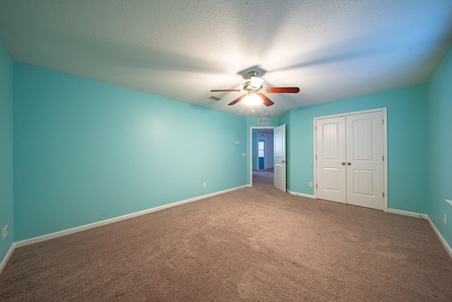 unfurnished bedroom with a closet, carpet flooring, ceiling fan, a textured ceiling, and baseboards