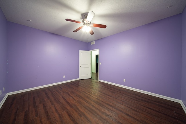 spare room with ceiling fan, dark wood-type flooring, a textured ceiling, and baseboards