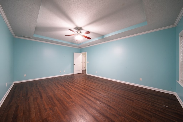 empty room with a textured ceiling, dark wood-type flooring, a raised ceiling, and baseboards