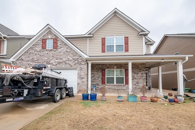 traditional-style home featuring a porch, a garage, brick siding, driveway, and a front yard