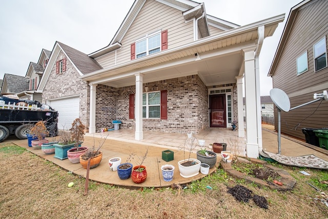 view of front of house with a garage, a porch, and brick siding