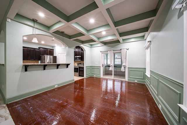 unfurnished living room featuring arched walkways, a decorative wall, coffered ceiling, beam ceiling, and light wood finished floors