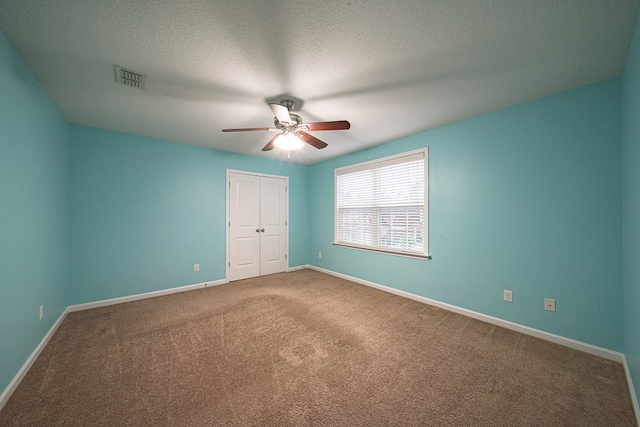 unfurnished bedroom with baseboards, visible vents, a textured ceiling, carpet flooring, and a closet