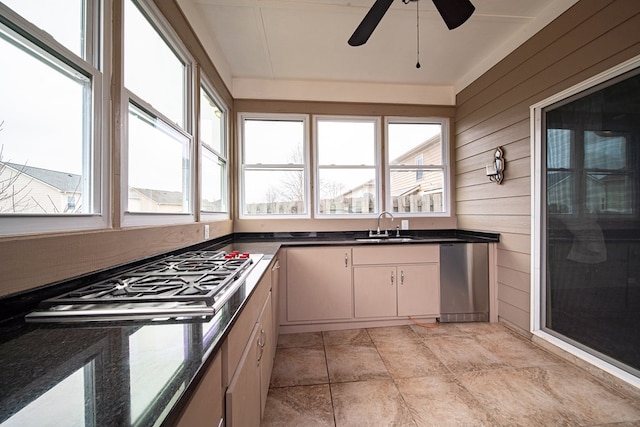 kitchen featuring a sink, wooden walls, gas stovetop, and a healthy amount of sunlight