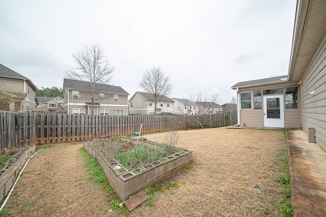 view of yard with a garden, a fenced backyard, and a residential view