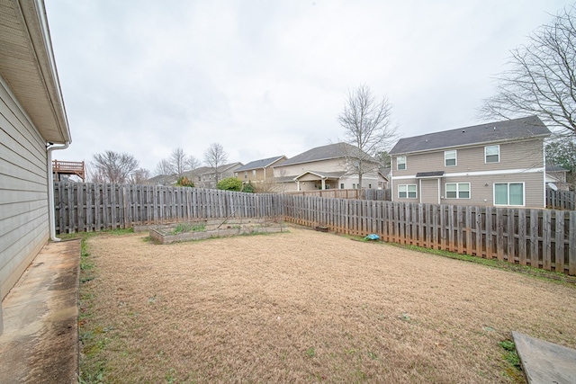 view of yard with a garden, a fenced backyard, and a residential view