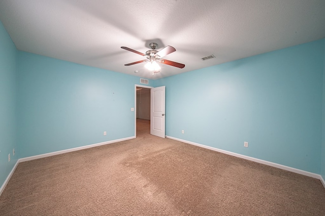 carpeted empty room with baseboards, a textured ceiling, visible vents, and a ceiling fan