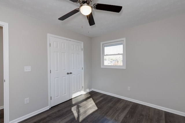 unfurnished bedroom with a textured ceiling, ceiling fan, a closet, and dark hardwood / wood-style floors