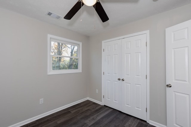 unfurnished bedroom featuring a textured ceiling, dark hardwood / wood-style flooring, a closet, and ceiling fan