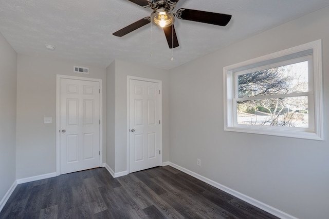 unfurnished bedroom with ceiling fan, dark hardwood / wood-style flooring, a textured ceiling, and a closet