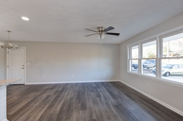 unfurnished room with ceiling fan with notable chandelier, a textured ceiling, and dark hardwood / wood-style flooring