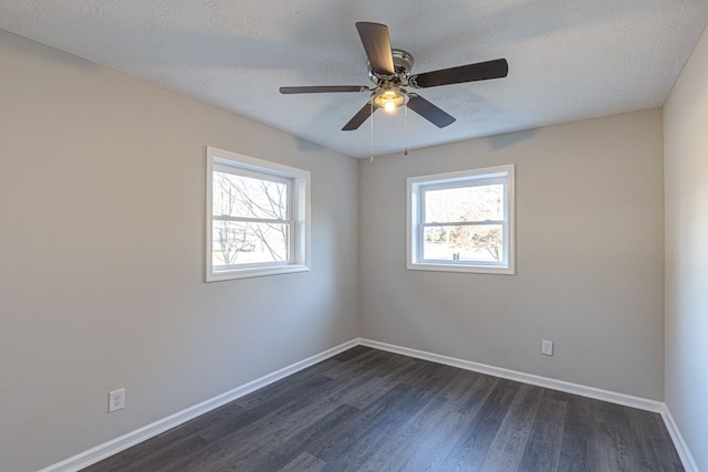 empty room featuring a textured ceiling, dark hardwood / wood-style floors, a wealth of natural light, and ceiling fan