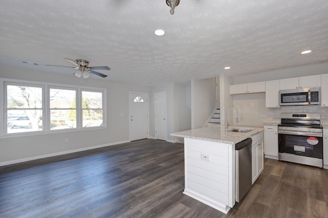 kitchen featuring stainless steel appliances, white cabinetry, a kitchen island with sink, and sink