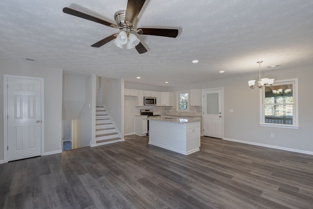 kitchen with a textured ceiling, white cabinets, stainless steel appliances, and decorative light fixtures