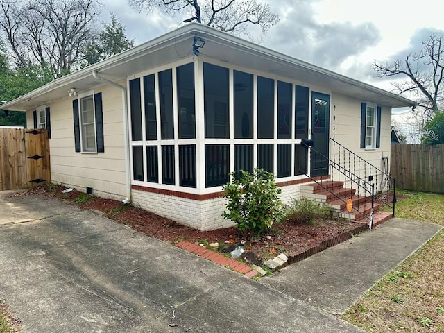 view of front of house with aphalt driveway, a sunroom, crawl space, fence, and a front lawn