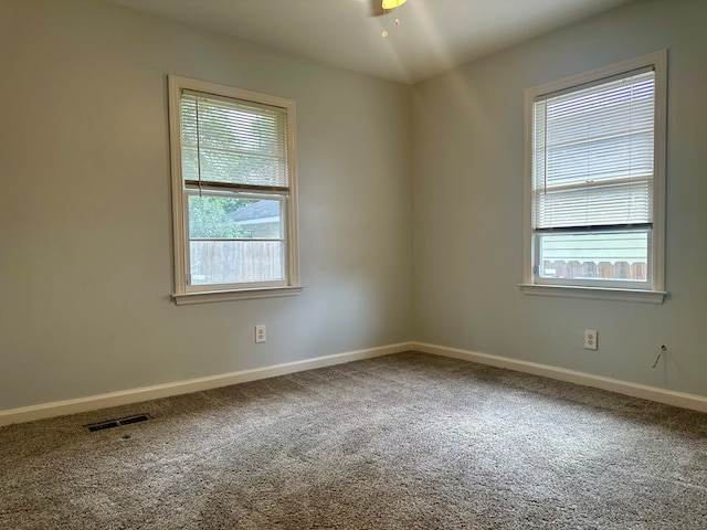 carpeted empty room with ceiling fan, a wealth of natural light, and baseboards