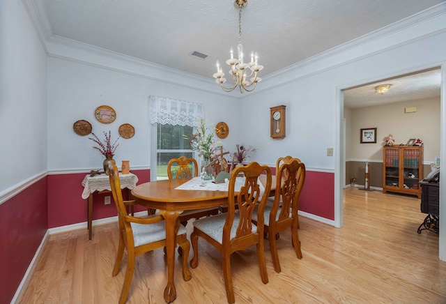 dining area with an inviting chandelier, crown molding, visible vents, baseboards, and light wood-type flooring