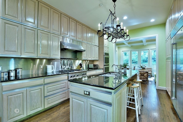 6528 Standing Boy Dr, Columbus, GA 31904 - kitchen featuring dark wood finished floors, an island with sink, a breakfast bar area, appliances with stainless steel finishes, and under cabinet range hood