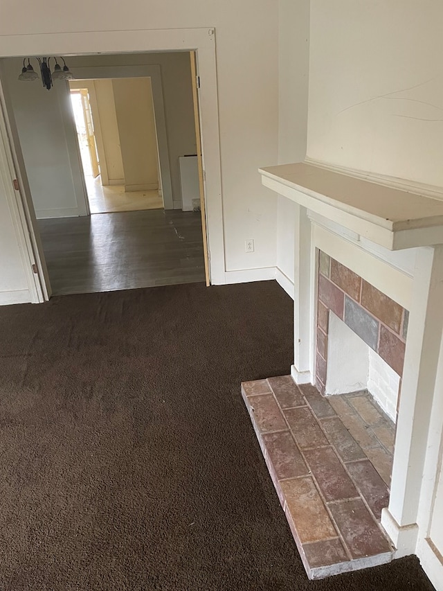 unfurnished living room featuring a fireplace and dark carpet