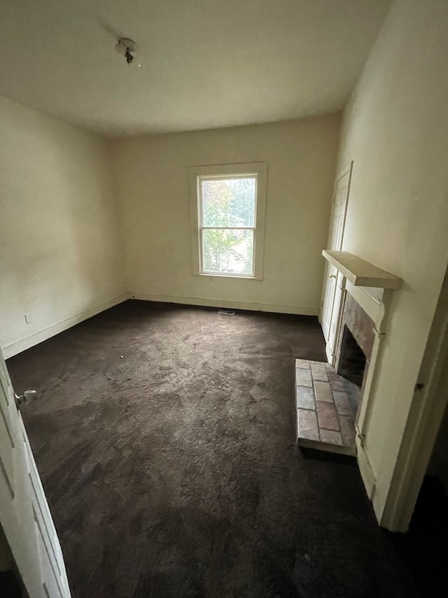 unfurnished living room with dark carpet and a tile fireplace