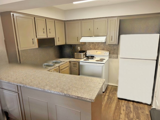 kitchen featuring sink, tasteful backsplash, dark hardwood / wood-style flooring, kitchen peninsula, and white appliances