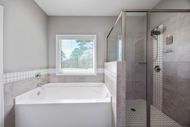 bathroom featuring a shower stall, a garden tub, and tile walls