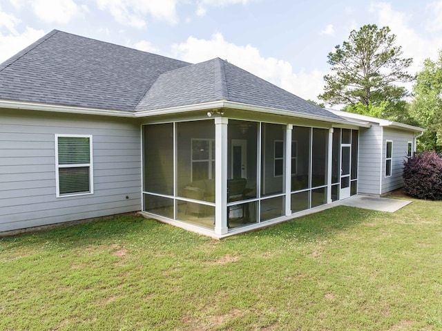 back of property featuring roof with shingles, a sunroom, and a yard